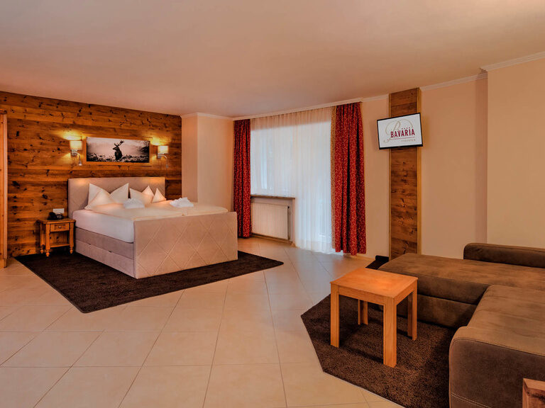 Das Bild zeigt die 2 Raum Suite "Hirsch" im Hotel Bavaria in Pfronten mit der großen Couch und dem gemütlichen Doppelbett für einen perfekten Aufenthalt