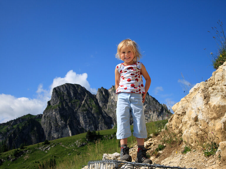 Ein kleines Mädchen steht auf einem Stein auf dem Breitenberg.